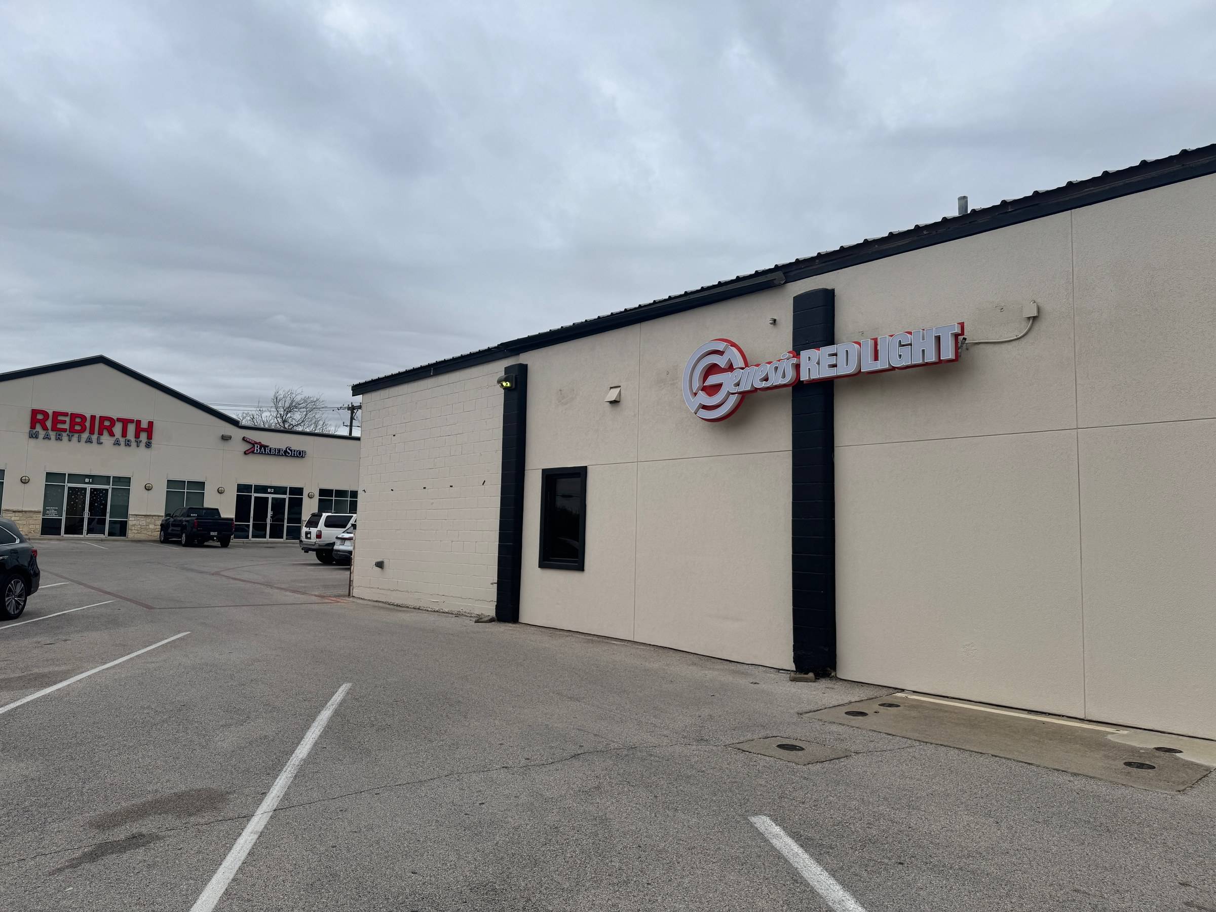The Genesis Red Light sign on the building at 103 N Bell Blvd, Cedar Park, with Rebirth Martial Arts across the parking lot