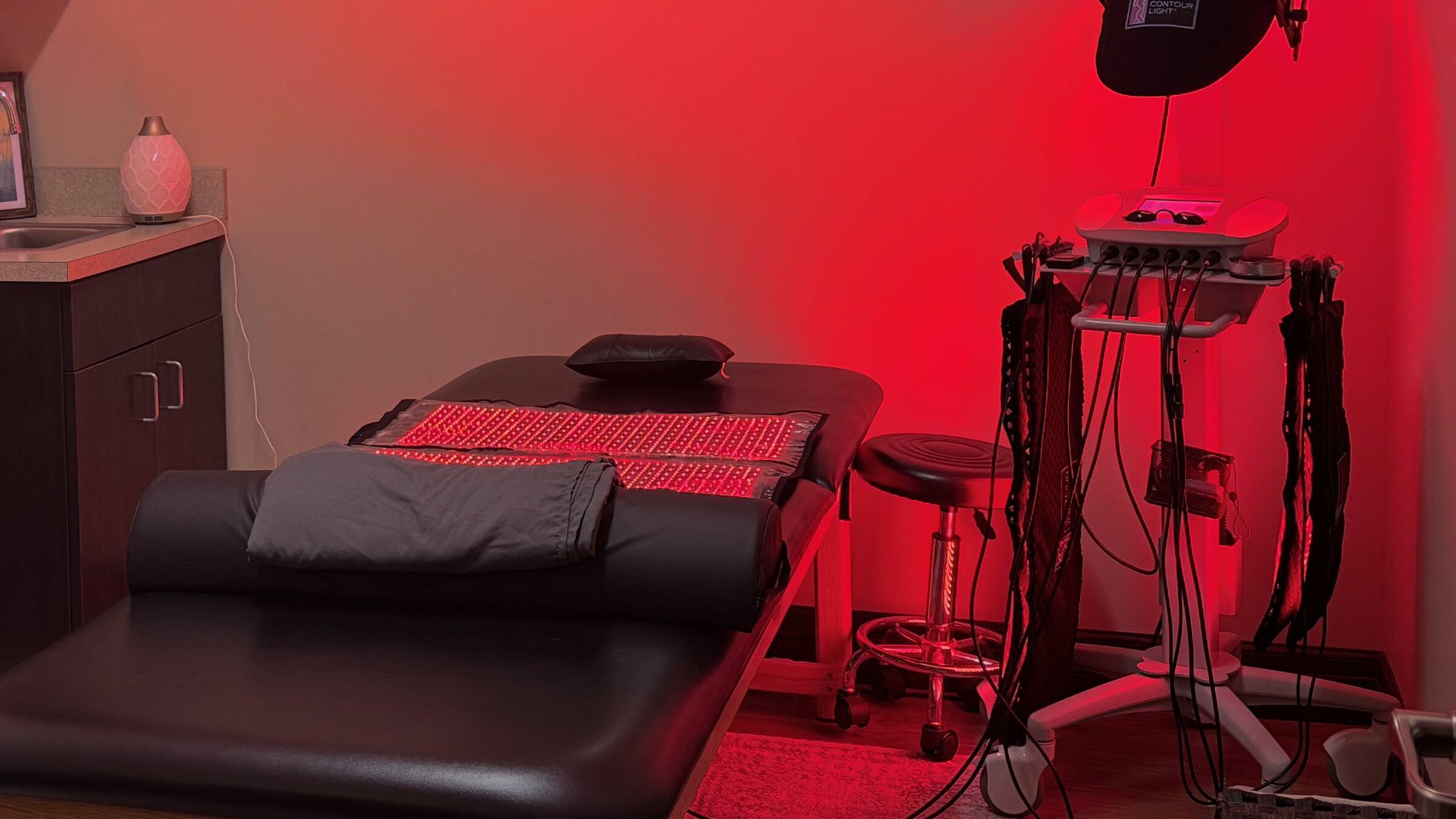 Private red light treatment room with a padded bed, red light pads and the Contour Light device