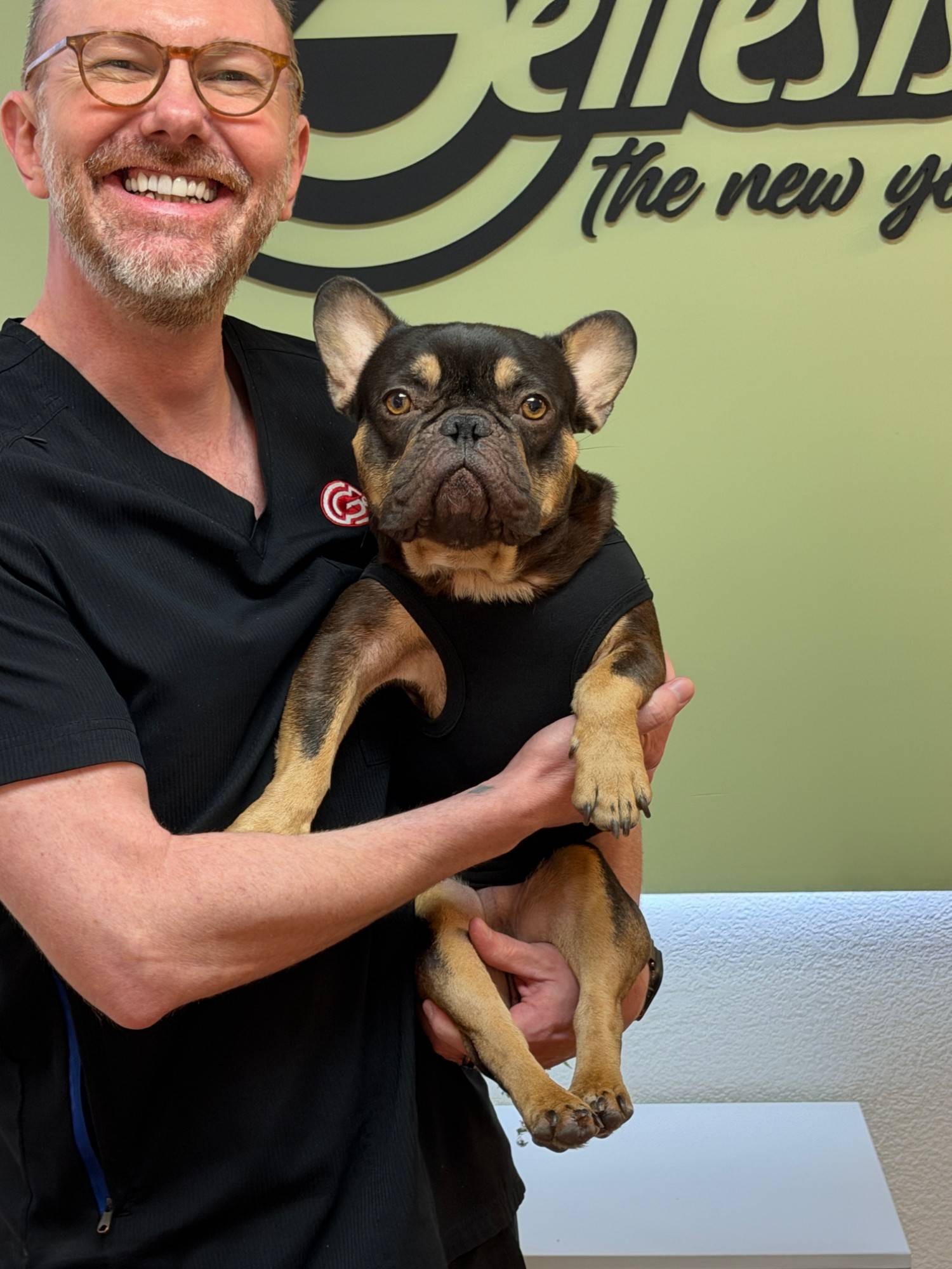 John from Genesis Red Light holding Kevin, the clinic’s French bulldog mascot